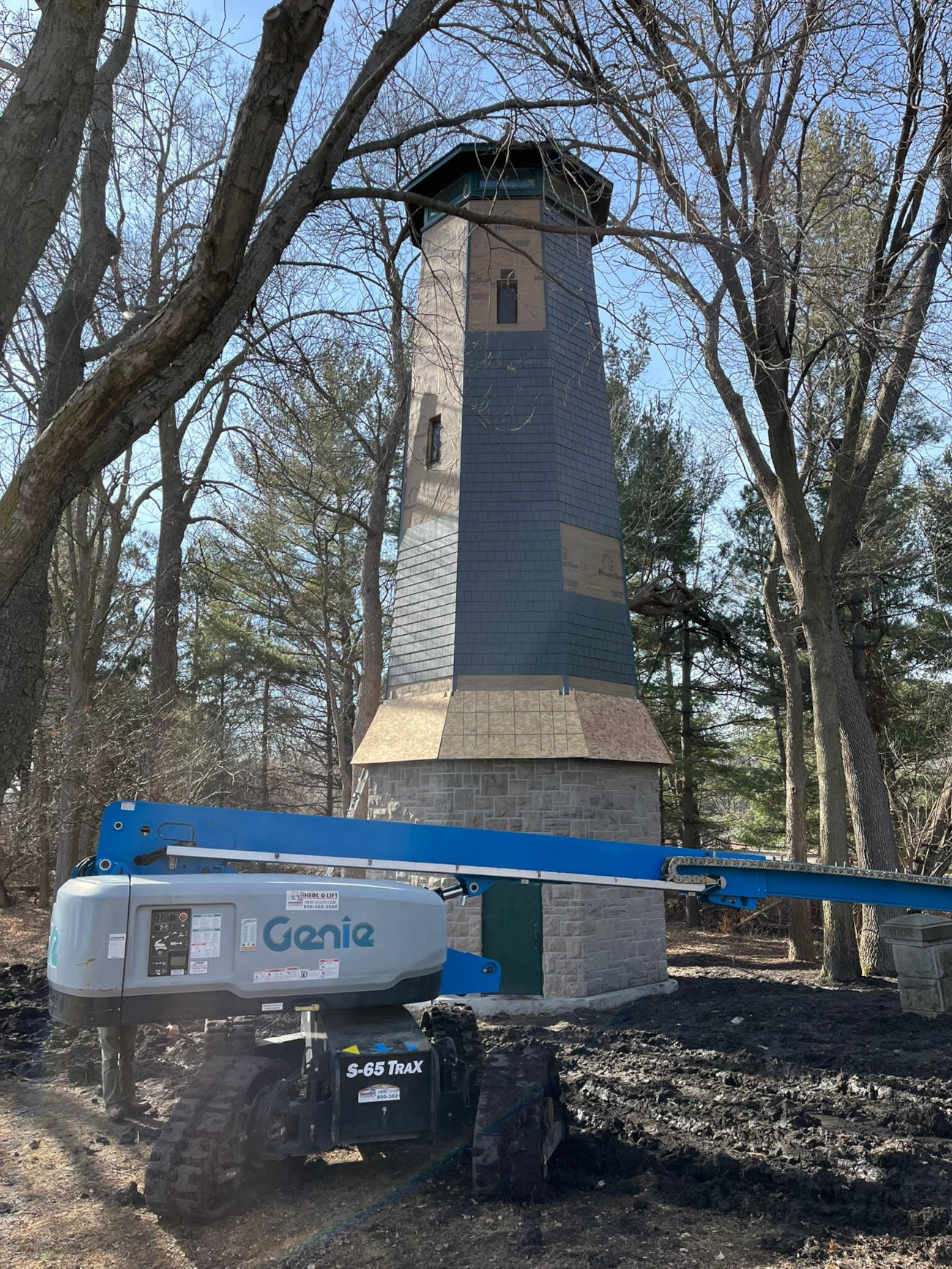 Historic stone and wood tower restoration project by Minnesota Structures with lift equipment on site